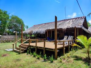 a house with a deck with chairs and a thatch roof at Cabaña con Deck Frente al Mar para 8 personas in Moñitos