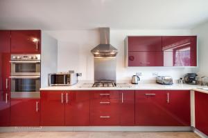 a kitchen with red cabinets and a stove at BEACHES - South Sands beach house in Torquay