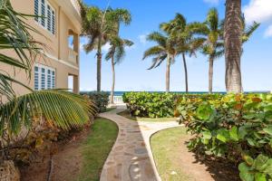 a walkway in front of a building with palm trees at Ocean Vibes near Rincón Beachfront Access Condo in Matias