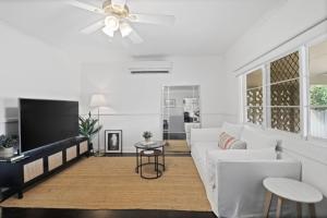 a white living room with a white couch and a tv at Mildas Cottage Hunter Valley in Cessnock