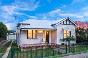 a white house with a fence in front of it at Mildas Cottage Hunter Valley in Cessnock