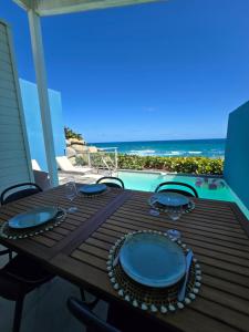 a wooden table with blue plates on a balcony with the ocean at Villa Aura in Oyster Pond