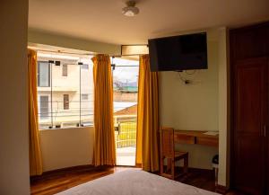 a bedroom with a bed and a desk and a window at Casa Qory in Cajamarca