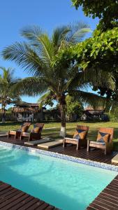 a pool with lounge chairs next to a palm tree at Vila Sereia Caraiva in Caraíva