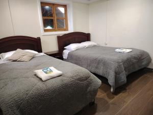 two beds in a room with towels on them at Hostal Casa Cotopaxi in Latacunga