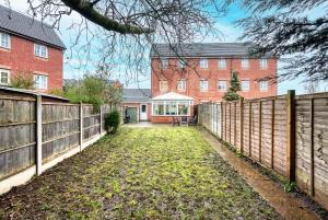 a fence in front of a brick building at Comfort Lodge - Modern 5 bed house w 2 bathrooms, parking & gardens in Solihull