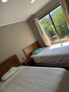 two beds in a small room with a window at Radal Riverside Lodge in El Torreón