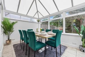 a dining room with a table and green chairs at Comfort Lodge - Modern 5 bed house w 2 bathrooms, parking & gardens in Solihull