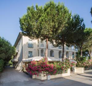 a building with trees and flowers in front of it at Hotel Dover Rooms & Coffee Adults Friendly in Cervia