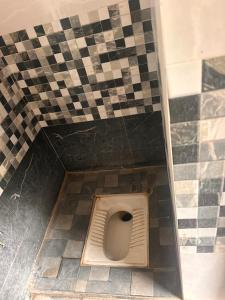 a toilet in a bathroom with a checkered floor at Jacobs Cottage KG-G1 in Thiruchendur