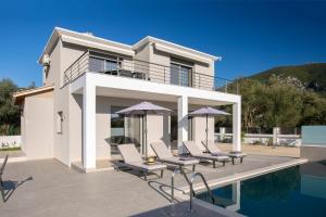 a villa with a pool and chairs and a house at Valora Villa in Nydri