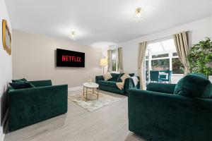 a living room with two green couches and a tv at Comfort Lodge - Modern 5 bed house w 2 bathrooms, parking & gardens in Solihull