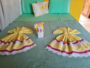 two dresses on top of a bed with a book at Village as casinhas in Uruçuca