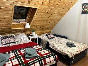 two beds in a room with a wooden wall at Górska Chata w Górach Bystrzyckich in Niemojów