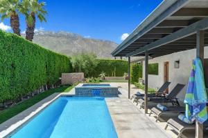 a swimming pool with two chairs and an umbrella at Alejo Olive Orchard - Alice Lodging in Palm Springs