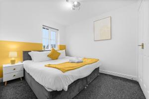 a bedroom with a large bed with a yellow blanket on it at Comfort Lodge - Modern 5 bed house w 2 bathrooms, parking & gardens in Solihull