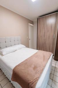 a bedroom with a large white bed with a wooden door at REFÚGIO FAMILIAR Jampa JP in João Pessoa