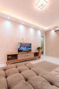 a living room with a couch and a flat screen tv at REFÚGIO FAMILIAR Jampa JP in João Pessoa