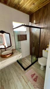 a bathroom with a glass shower and a toilet at Village as casinhas in Uruçuca
