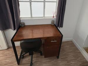 a wooden desk with a chair in front of a window at Departamento céntrico y cómodo La Casona in Xalapa