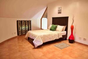ein Schlafzimmer mit einem Bett und einer roten Vase in der Unterkunft Madlabeezy in Kempton Park