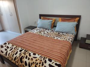 a bedroom with a bed with a leopard print blanket and pillows at L'Ambre in Hammamet