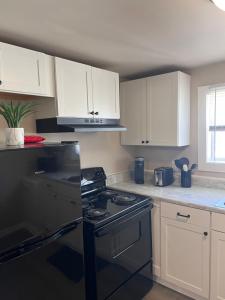 a kitchen with a black stove and white cabinets at Skipper Apt #4 in Rockingham
