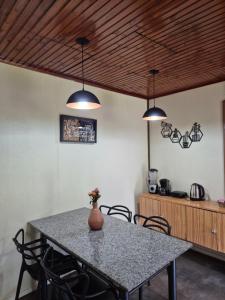 a dining room table with three lights and a vase on it at Casa completa in Caçapava do Sul