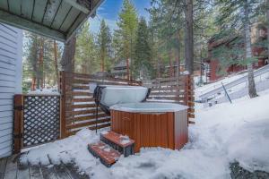 a hot tub sitting on a deck in the snow at Zephyr Chalet Steps from Zephyr Cove in Glenbrook