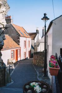 an alley with buildings and a street with flowers at The Merchants House in Pittenweem