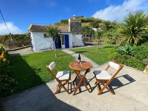 a table with three chairs and a bottle of wine at Villa Pico de Mafra in Mosteiros