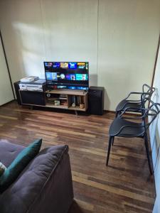 a living room with a flat screen tv and a chair at Casa completa in Caçapava do Sul