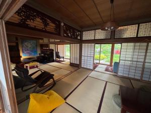 a room with chairs and a table and windows at 離れの宿 かぶろの庭 離れの宿 KuRA in Matsukawa