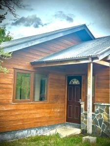 a wooden house with a brown door and a stone at Cabañas Raíces de la Patagonia in Coihaique