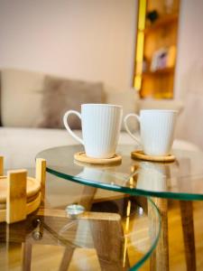 two coffee cups sitting on a glass table at SOL LUX Tuzla in Tuzla