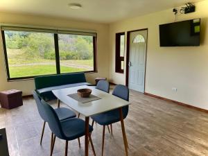a living room with a table and chairs and a tv at Cabañas Raíces de la Patagonia in Coihaique