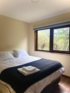 a bedroom with a bed with two towels on it at Cabañas Raíces de la Patagonia in Coihaique