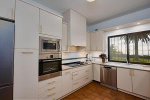a kitchen with white cabinets and a window at Villa El Capricho in Mijas +25 photos
