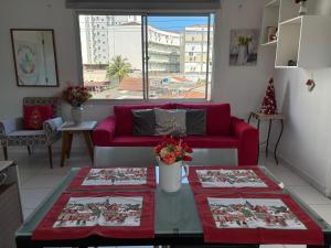 a living room with a red couch and a table at Espaço Zen - Equilíbrio da Alma in Guarujá