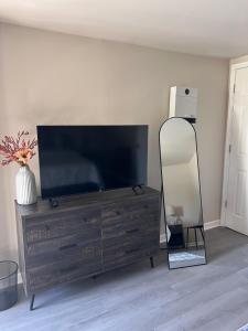 a living room with a television on a dresser with a mirror at Skipper Apt #4 in Rockingham