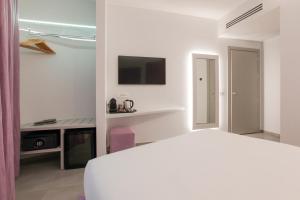 ein weißes Schlafzimmer mit Bett und Fernseher in der Unterkunft The Grove in Mailand