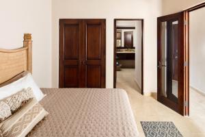 a bedroom with a bed with a wooden door at Apartamento en Los Cabos - Misiones del Cabo in Cabo San Lucas
