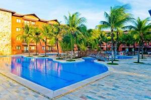 a swimming pool with palm trees and a building at Kariri Beach Waterfront Retreat in Caucaia