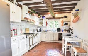 a kitchen with white cabinets and a table with chairs at Maison Avec Piscine Couverte in Fervaques