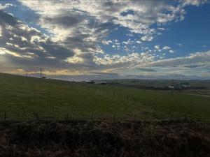 a field with a fence and a cloudy sky at Cunningair, Kirkwall, Orkney - OR00447F in Kirkwall