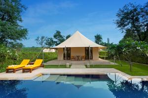 a tent with chairs and a swimming pool in front of a house at The Oberoi Sukhvilas Spa Resort, New Chandigarh in Chandīgarh