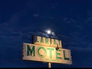 a neon sign for a parking lot with a moon at Lariat Motel in Moriarty
