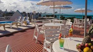 a rooftop deck with tables and chairs with a view of the ocean at Flat tambau in João Pessoa