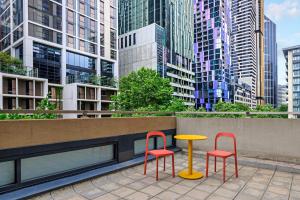 two chairs and a table on a balcony with buildings at lyf on Elizabeth Melbourne in Melbourne