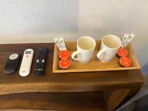 a wooden tray with two cups and a remote control at Nomads Kite House in El Cuyo